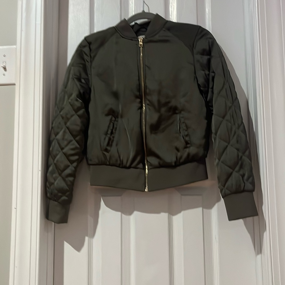 Green jacket with pockets and a diamond pattern down the sleeve with a zipper